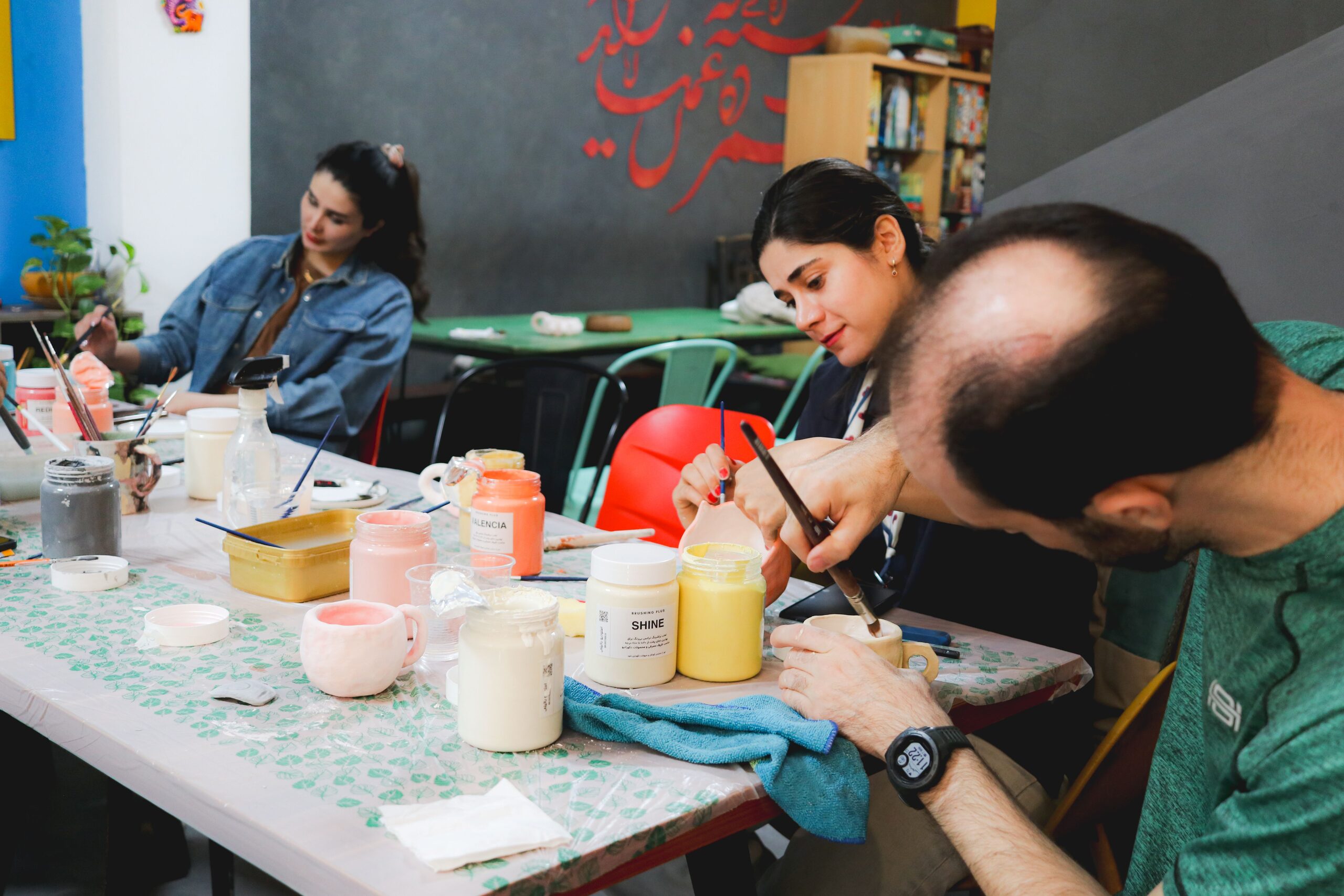 Plusieurs artistes peignent des tasses autour d’une table